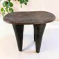 Tall dark hardwood Senufo stool with four long tapered legs, styled beside a plant