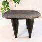 Dark hardwood Senufo stool with a broad, dished seat, styled beside a plant