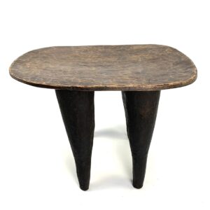 Front view of the Senufo stool with a lighter worn seat and dark tapered legs on a white background