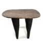Front view of the Senufo stool with a lighter worn seat and dark tapered legs on a white background
