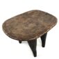 Angled view of the carved seat of the Senufo stool with a lighter worn seat and dark tapered legs