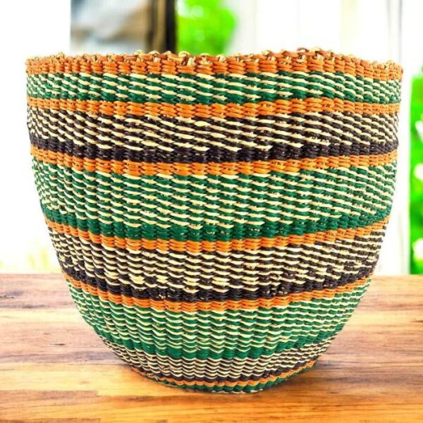 bashiri-woven-planter-basket-green-orange-diagonal Handwoven planter basket in green, orange and black diagonal stripe pattern on a timber surface
