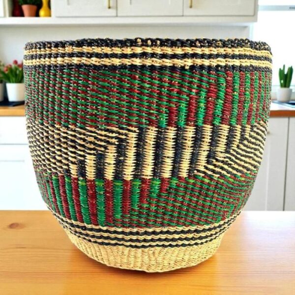 bashiri-woven-planter-basket-green-red-black-geometric Handwoven planter basket in green, red and black geometric pattern on a timber bench