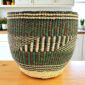 Handwoven planter basket in green, red and black geometric pattern on a timber bench