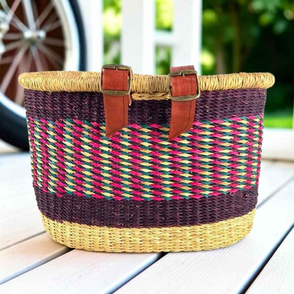 Purple Bolga bike basket with pink, green, and natural diagonal weave, leather straps and buckles