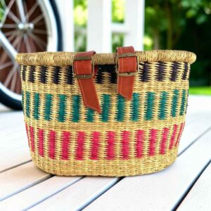 Natural Bolga bike basket with navy zigzag, teal diamonds, and pink stripes, leather straps and buckles