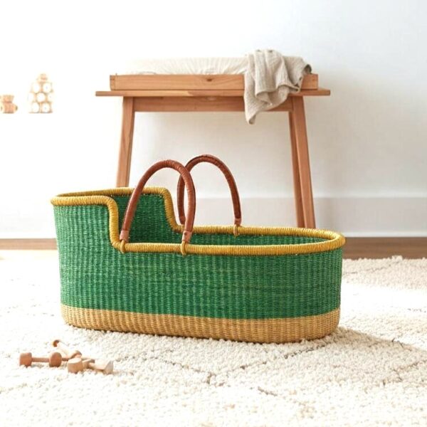 Green Moses baby basket with a yellow rim on a rug in a nursery
