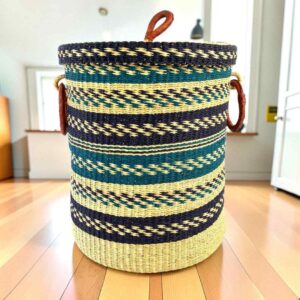 Closed bolga laundry basket, navy and teal chevron stripes over natural straw, with leather ring handles