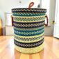 Closed bolga laundry basket, navy and teal chevron stripes over natural straw, with leather ring handles