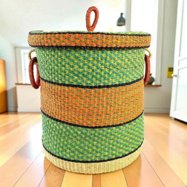 Closed bolga laundry basket, green, orange and black stripes over natural straw, with leather ring handles