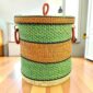 Closed bolga laundry basket, green, orange and black stripes over natural straw, with leather ring handles