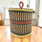 Closed bolga laundry basket, black geometric weave over natural straw with a green and orange band