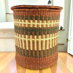 a woven laundry basket in natural, brown, and olive colours, with a lid.