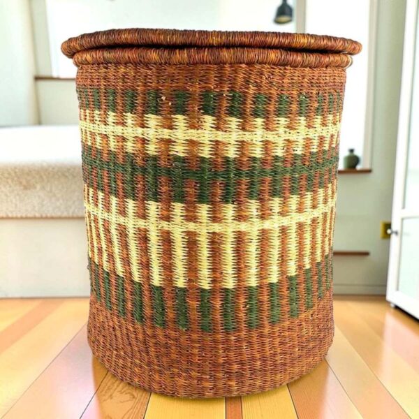 a woven laundry basket in natural, brown, and olive colours, with a lid.