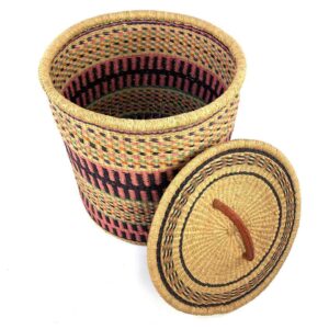 The closed laundry basket with its lid off, showing coral pink and black bands with olive stripes and a woven lid
