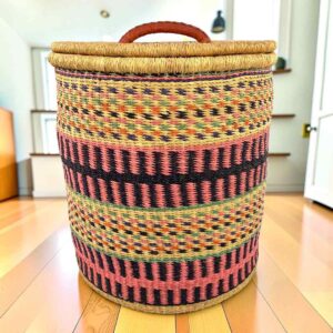 Closed laundry basket with coral pink and black bands with olive stripes and a woven lid
