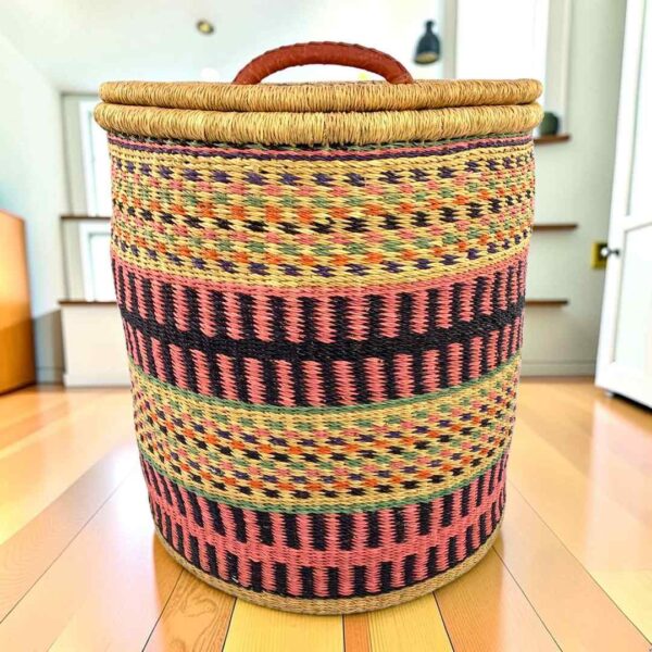 closed-laundry-basket-0305-ember-pink-black-african-bashiri-main Closed laundry basket with coral pink and black bands with olive stripes and a woven lid