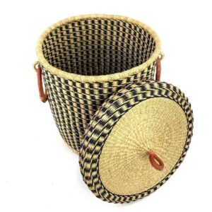 The closed laundry basket with its lid off, showing a black and natural check, a woven lid and leather ring handles