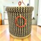 Closed laundry basket with a black and natural check, a woven lid and leather ring handles