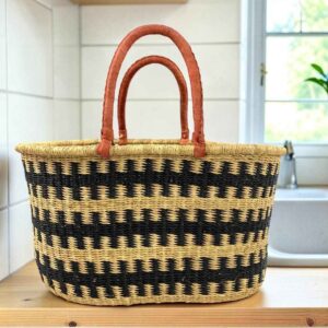 Extra large oval Bolga basket with an all-over black and natural check and leather handles, on a wooden kitchen bench