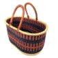 Angled view of the extra large oval Bolga basket with rust orange and navy bands, showing the woven interior