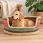 Medium Bolga pet basket in coral, pink, green and brown stripes with a golden dog lying inside