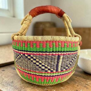 Medium round Bolga basket with coral pink, green and navy zigzag pattern, leather handles