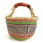 Angled view of the medium round Bolga basket showing coral pink, green and navy zigzag pattern