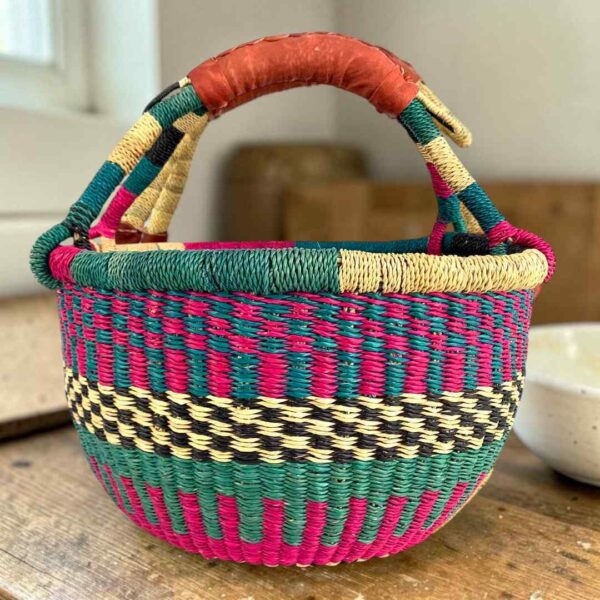 Medium round Bolga basket with a teal and magenta checker weave with a cream-and-black band, leather handles