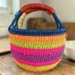 Medium round Bolga basket with a navy rim with orange, lime green and magenta bands, leather handles