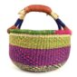 Angled view of the medium round Bolga basket showing a natural top band flecked green and orange, with a magenta and navy diamond pattern below