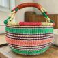 Medium round Bolga basket with a natural-and-red rim with green, purple and coral horizontal stripes, leather handles