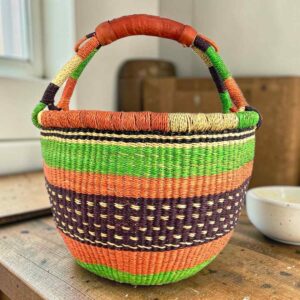 Medium round Bolga basket with an orange-and-cream rim with green, orange and plum bands, the plum band with cream dot detail, leather handles