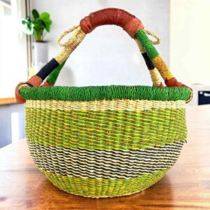 Fresh-toned banded medium round Bolga basket with leather-wrapped handle, on a timber table