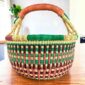 Rich-toned checked medium round Bolga basket with leather-wrapped handle, on a timber table