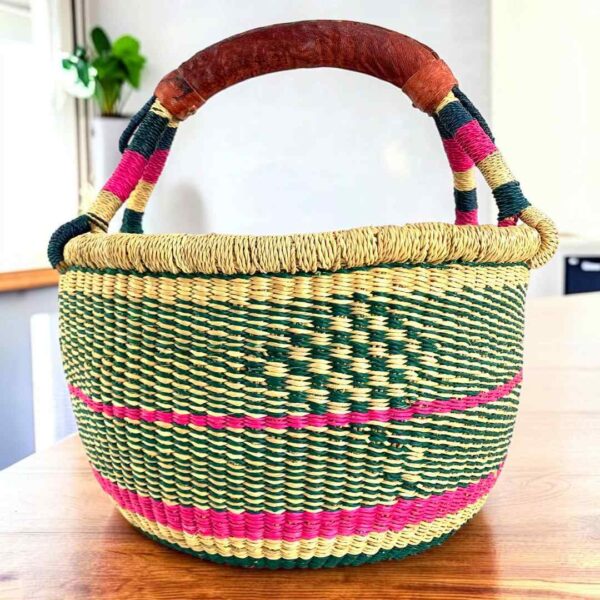 Two-tone diamond-pattern medium round Bolga basket with leather-wrapped handle, on a timber table