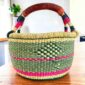 Two-tone diamond-pattern medium round Bolga basket with leather-wrapped handle, on a timber table