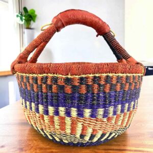 Warm-toned zigzag medium round Bolga basket with leather-wrapped handle, on a timber table