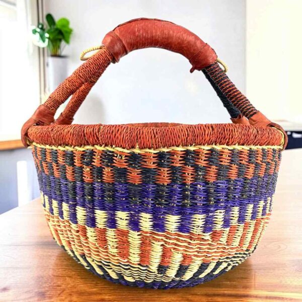 Warm-toned zigzag medium round Bolga basket with leather-wrapped handle, on a timber table