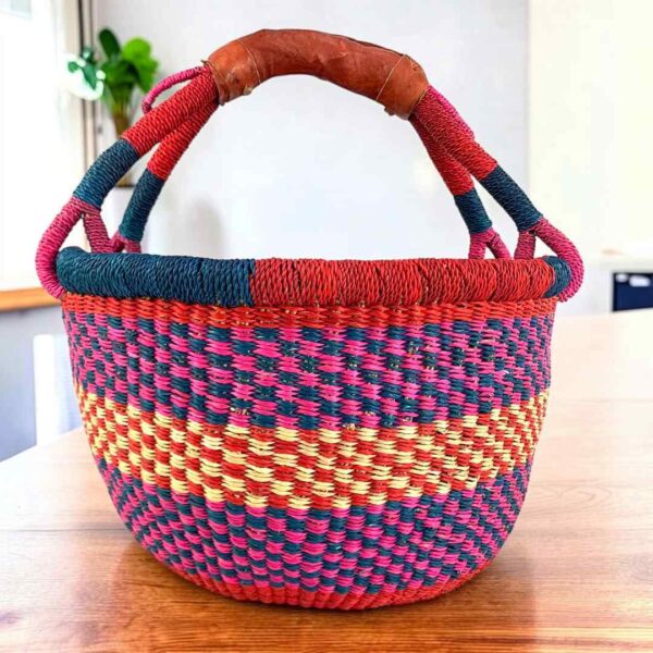 Bright checked medium round Bolga basket with leather-wrapped handle, on a timber table