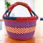 Bright checked medium round Bolga basket with leather-wrapped handle, on a timber table