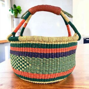 Deep-toned striped medium round Bolga basket with leather-wrapped handle, on a timber table