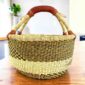 Neutral-toned medium round Bolga basket with a dark diagonal pattern with leather-wrapped handle, on a timber table