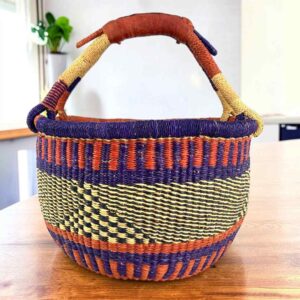 Deep warm-toned checked medium round Bolga basket with leather-wrapped handle, on a timber table