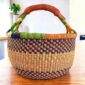 Multi-tone checked medium round Bolga basket with leather-wrapped handle, on a timber table