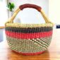Warm and dark banded medium round Bolga basket with leather-wrapped handle, on a timber table
