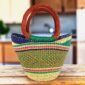 Mini market basket with bright rim bands over a soft, earthy patterned body and leather-wrapped handles
