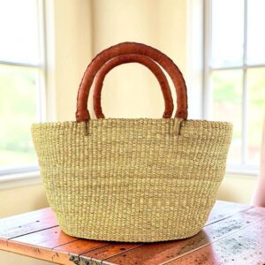 a woven shopping basket in natural colour with tan leather handles