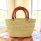 a woven shopping basket in natural colour with tan leather handles