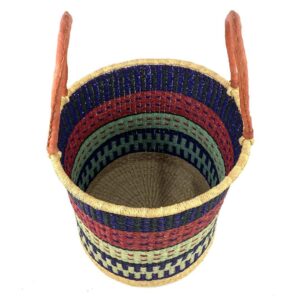Angled view of the open laundry basket with navy and red bands with a pale green check and tall leather handles